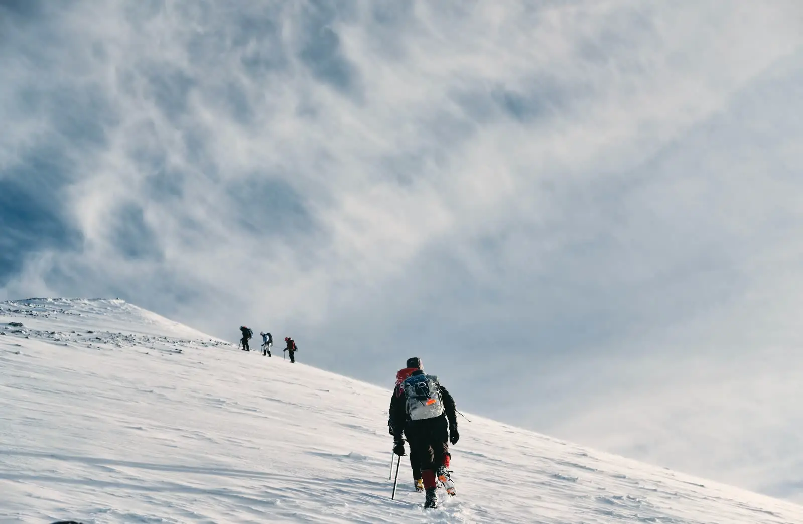A field team ascending a snowy ridge.