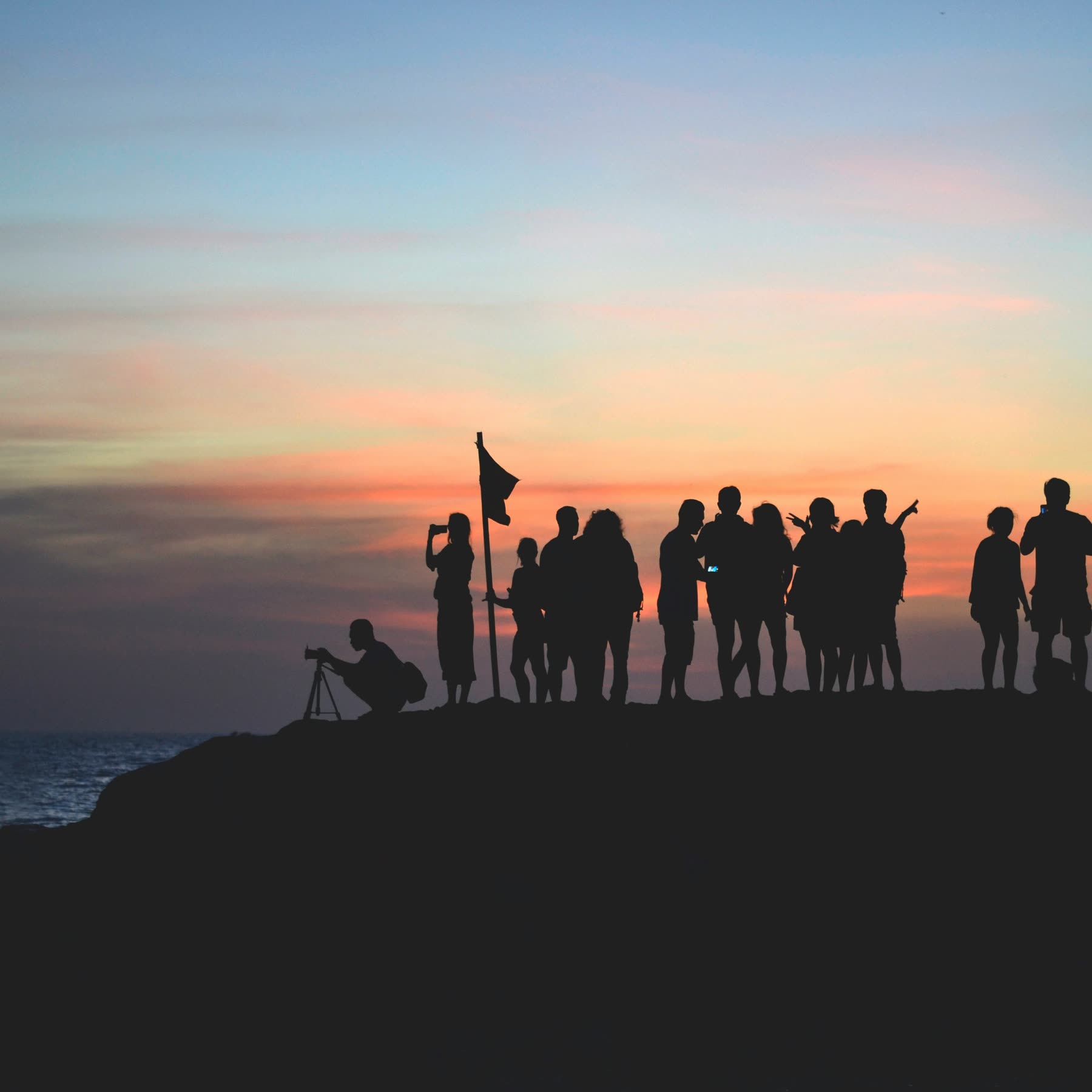 The Coverden team silhouetted on a headland at dusk, flag raised.